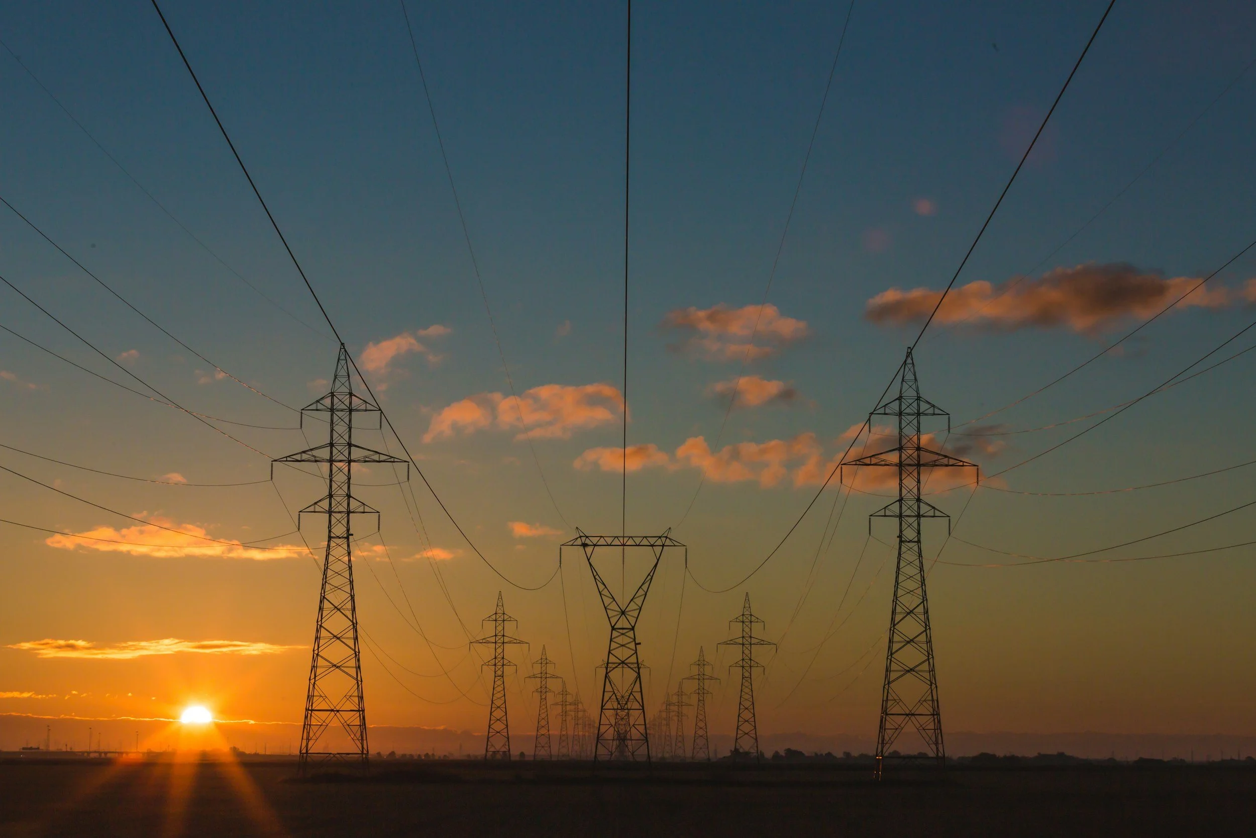 Transmission towers silhouetted against a sunrise
